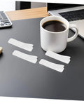 100 Pack Double Sided Hook And Loop Strips With White Pet Film Backing 2.5x10cm on a desk next to a coffee cup.