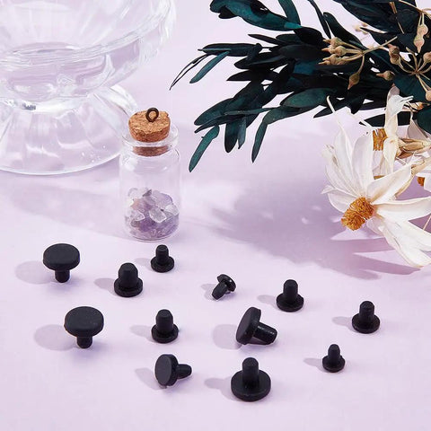 Cool 50 Pack Black Silicone Hole Plugs In 5 Sizes For Pipe And Bottle Ends Waterproof Flexible Rubber Stoppers That Fit Tight Without Leaking Any Liquid Or Mess Up Your Daily DIY Hacks At Home. Black silicone hole plugs in assorted sizes on a pink surface