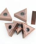 Top view of five brown triangular carbide turning inserts with center mounting hole for CNC lathes
