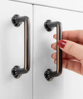 Hand holding 10 Pack 3 Inch Hole Centers Oil Rubbed Bronze Cabinet Pulls with Clover Design, installed on white cabinet