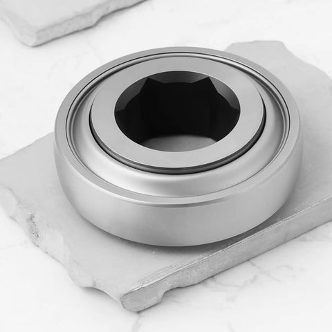 Tough As Nails Rock Solid Hex Bearing 210RRB6 One Inch Half X Ninety Millimeter Heavy Duty Replacement For John Deere Farm Tractors, shown on a stone.