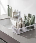 Eighteen Pack Slick Slim Plastic Baskets For Narrow Drawer Setup. Slim white basket holding various beauty products on a countertop.