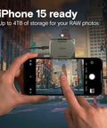 Person using iPhone 15 with Crucial adapter for photo capture, displaying the city's skyline for RAW imagery.