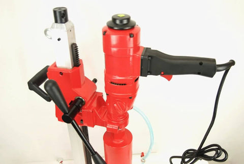 Red core drill with black grip handle mounted on a stand; power cord attached for concrete coring.