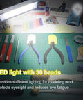 Portable Model Making Workbench With LED Lights And Magnifier All In One Cutting And Assembly Kit For DIYers Includes Pliers Holder Gridded Adhesive Cut Mats Plastic Storage Drawers Display Panel on a work surface with tools and LED light visible