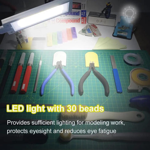 Portable Model Making Workbench With LED Lights And Magnifier All In One Cutting And Assembly Kit For DIYers Includes Pliers Holder Gridded Adhesive Cut Mats Plastic Storage Drawers Display Panel on a work surface with tools and LED light visible
