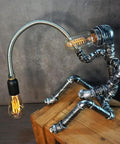 Dope Handcrafted Steampunk Water Pipe Robot Desk Lamp With Vintage Industrial Vibe For Bedside And Desk, placed on a wooden box.