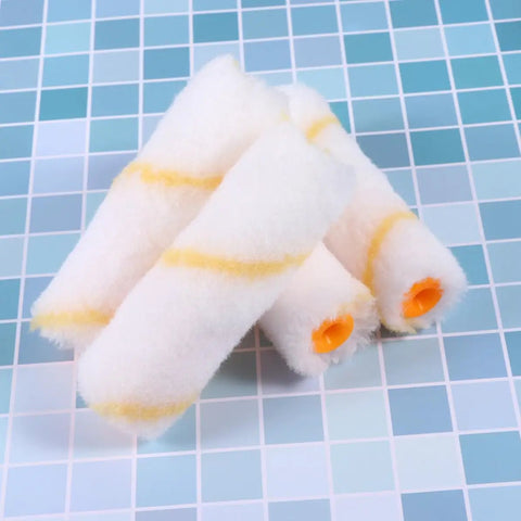 Thirty Piece Mini Paint Roller Sleeves With High Density Foam To Banish Ugly Track Lines And Deliver A Smooth As Silk Wall Finish While Providing Quick Dry Coverage That Always Hits The Spot Without Breaking The Bank. Close-up of four white foam roller sleeves with yellow stripes.