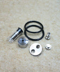 Front view of waterjet check valve repair kit components: aluminum discs, clear plunger with spring, black O-rings, and metal fittings.