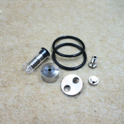 Front view of waterjet check valve repair kit components: aluminum discs, clear plunger with spring, black O-rings, and metal fittings.