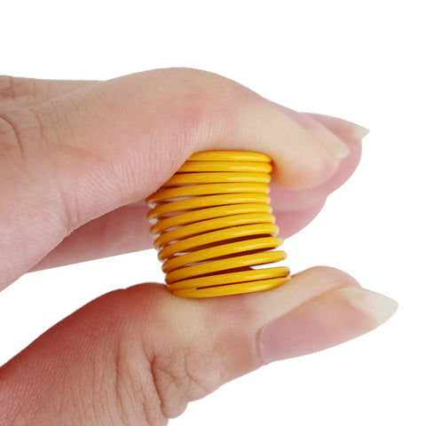 Hand holding yellow alloy spring from Metal Shock Spring Set For One Tenth Scale RC Crawlers Rad Upgrade For TRX4 And Axial SCX10 Platforms.