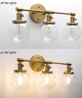 Three Light Vintage Industrial Bathroom Vanity Wall Sconce With Handblown Clear Glass Globes And Antique Gold Finish, 25.2 Inch Wide Triple Light Bath Fixture, shown with lights on and off.