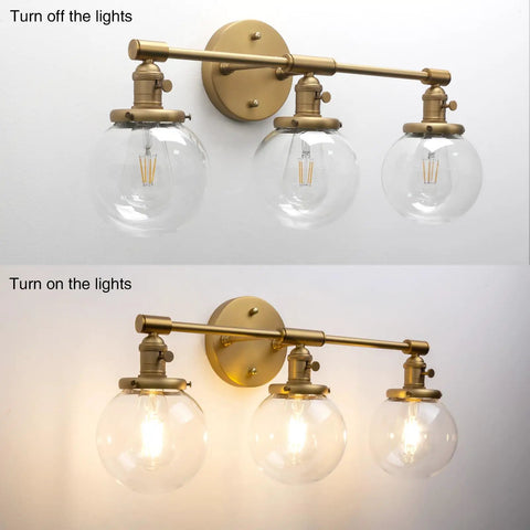 Three Light Vintage Industrial Bathroom Vanity Wall Sconce With Handblown Clear Glass Globes And Antique Gold Finish, 25.2 Inch Wide Triple Light Bath Fixture, shown with lights on and off.