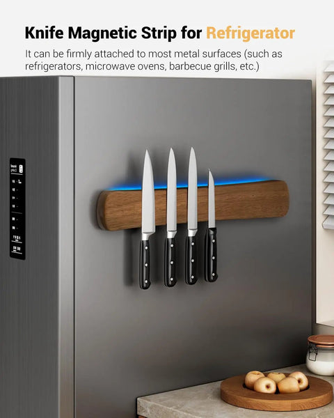 Magnetic Knife Holder For Wall And 16 Inch Acacia Wood Knife Strip mounted on a fridge holding four knives in a kitchen setting