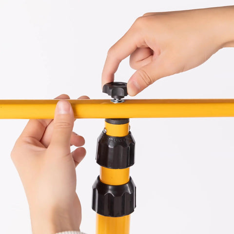Hands adjusting yellow Adjustable Foldable Metal Tripod Archery Target Stand For Backyard And Shooting Range Bow And Arrow Target Holder