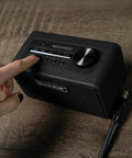 Person adjusting Beam Mini Portable Guitar Amp With NAM Compatibility, 17 Models, 35 Plus Effects, USB C And Bluetooth on wood surface.