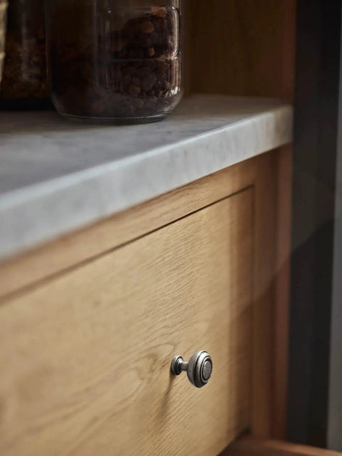 Straight Up Vintage Vibes With These Killer Weathered Nickel Cabinet Knobs Packed In A Six Pack For Instant Counter Makeovers detailed close-up of a weathered nickel cabinet knob on a wooden drawer.