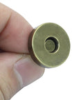Close-up of a hand holding an 18mm magnetic snap from the 40 Sets Magnetic Snaps For Purses And Bags, 18mm Rustproof Fasteners Replacement Kit In 4 Colors.