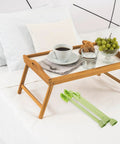 Breakfast tray with coffee, water, and fruit on bed. Foldable Table Legs Set Of 4 For Furniture And Laptop Desks in light green beside it.