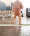 Child walking in room with Heavy Duty Ten Foot Floor Cord Cover With 3 Channel PVC Cable Protector on wooden floor
