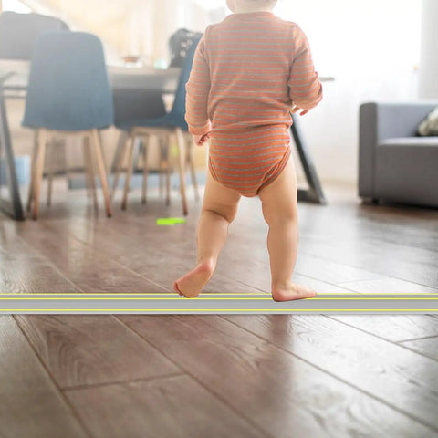 Child walking in room with Heavy Duty Ten Foot Floor Cord Cover With 3 Channel PVC Cable Protector on wooden floor