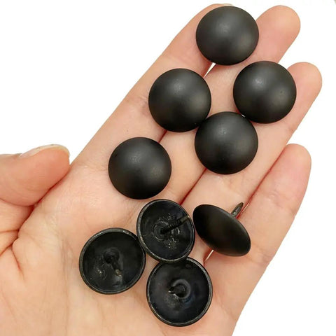 Top Shelf Matte Black Upholstery Tacks 100 Piece Set Heavy Duty Metal Thumb Tacks in hand, showing black round heads and metal prongs.