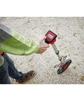 Person holding Rugged 12 Inch Digital Measuring Wheel With IP54 Backlit Display on rough surface for distance tracking.