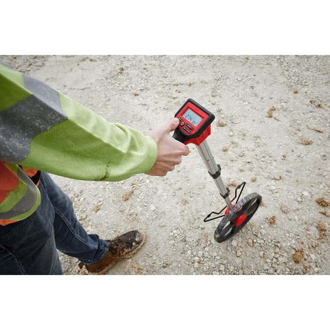 Person holding Rugged 12 Inch Digital Measuring Wheel With IP54 Backlit Display on rough surface for distance tracking.