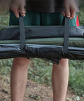 Person holding a rolled-up tent with straps, showcasing 4 Pack Heavy Duty Luggage Tie Straps Featuring Swivel Hog Ring Hooks For Roof Rack Cargo And Truck Bed Hauling Secure Your Gear With Zero Sweat On Long Drives.