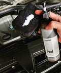 Hand holding Perl Coat Plastic And Rubber Protectant For Cars, Revives Dull Rubber, Plastics, Vinyl, Leather And Engine Bay Surfaces