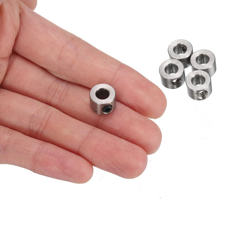 Hand holding a 5mm Bore Stainless Steel Shaft Collar with Set Screw from 12 Pack 5mm Bore Stainless Steel Shaft Collars With Set Screws 10mm Outside Diameter 7mm Wide Landing Gear Stopper Wheel Collar With Hex Wrench For Precise Positioning Spacing And Bearing Surface Applications with additional collars in background.