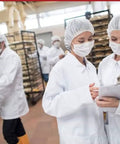 Workers in a food facility wearing Disposable Bouffant Hair Net Cap 21 Inch White Spun Bounded Polypropylene Head Cover 100 Count