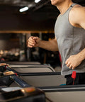 Man running on treadmill with red Treadmill Safety Key With Magnet Lock Replacement Kit attached to shorts in gym setting.