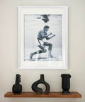 A framed photo of a person underwater above a shelf with modern black vases.