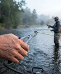 Close-up of 2 Pack Stainless Steel Fishing Pliers With Lanyard in use, cutting fishing line by river, showing durable beefy grip.