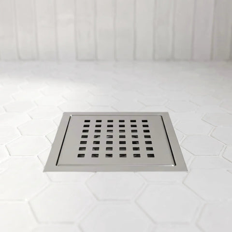 Modern Square Shower Drain With Brushed Nickel Finish on white hexagon tile floor, rust resistant grid cover in smooth finish.