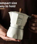 Stovetop Espresso Maker With Double Valve Tech Italian Moka Pot in compact size held in hand for easy brewing on gas or electric stove.