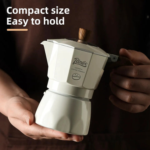 Stovetop Espresso Maker With Double Valve Tech Italian Moka Pot in compact size held in hand for easy brewing on gas or electric stove.