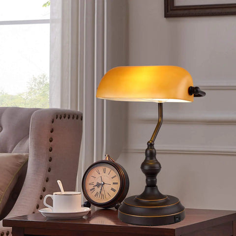Jade Green Glass Vintage Banker Desk Lamp With Antique Brass Finish on a wooden side table next to a clock and cup in a cozy room.