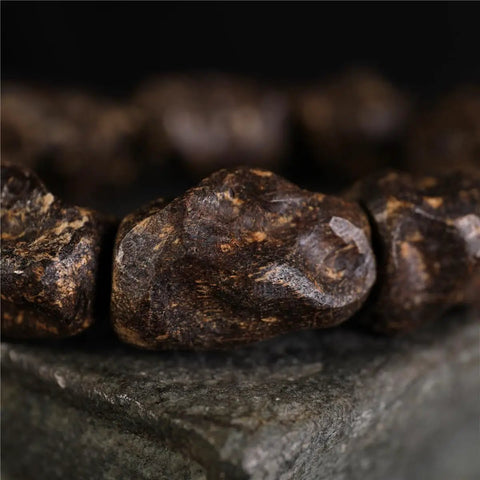 Close-up of Dope Agarwood Sinensis Jewelry Unisex Adjustable Bracelet with natural burl patterns on aged material.