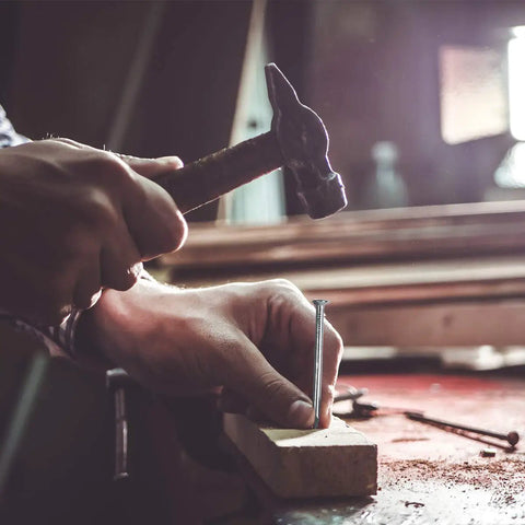 Person using hammer to drive nail into wood, depicting use of 400 Piece Hardware Nails Kit For Picture Hanging Galvanized Nails