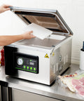 Pro Grade Chamber Vacuum Sealer Packs A Solid Punch With Sturdy 16 Inch Seal Bar And Whisper Quiet Motor, user adding a bag.