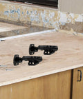 Three Pack Black Stainless Steel Full Overlay Concealed Cabinet Hinges With Soft Close Dampers on kitchen countertop