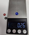 Anodized aluminum washers in blue and black on a digital scale displaying 0.26g, 60Pcs M4 Counterbore Washers Anodized Aluminum Alloy Black For RC FPV Drones PCs Toys Mechanical Accessories Head Washers Gaskets Cup Shims Screw Hardware.