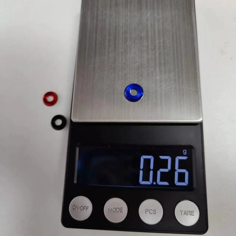 Anodized aluminum washers in blue and black on a digital scale displaying 0.26g, 60Pcs M4 Counterbore Washers Anodized Aluminum Alloy Black For RC FPV Drones PCs Toys Mechanical Accessories Head Washers Gaskets Cup Shims Screw Hardware.