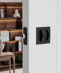 Matte Black Pocket Door Lock Set In Zinc Alloy, 2-3/8 Backset installed on white interior door with square handles.