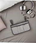 Gray Bed Rail Organizer Bag With Adjustable Strap And Four Storage Pockets beside headphones on bed