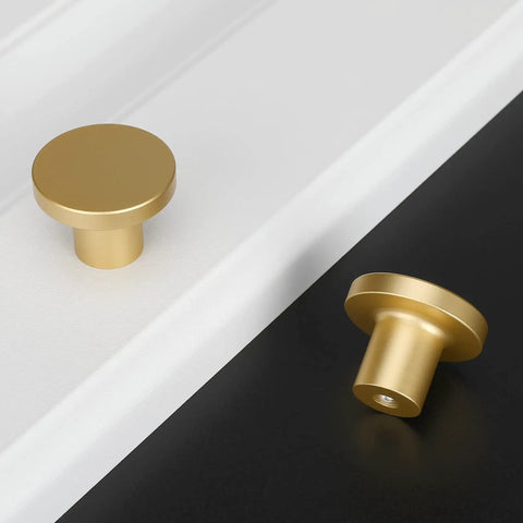 Gold cabinet knobs on white and black surfaces displaying a round design, not featuring Matte Black Cabinet Knobs 10 Pack.