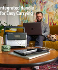Yeti Portable Power Station 499 Watt Hour LiFePO4 Battery on table next to man using laptop on couch.