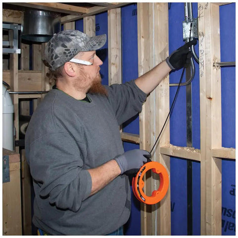 Electrician using Flat Steel Electrical Fish Tape Twenty Five Foot One Quarter Inch Wide Spring Steel With Slim Plastic Tip for wiring